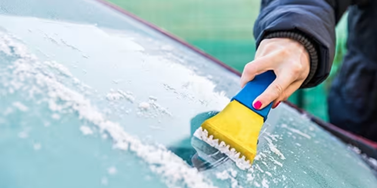 Woman scraping ice off car