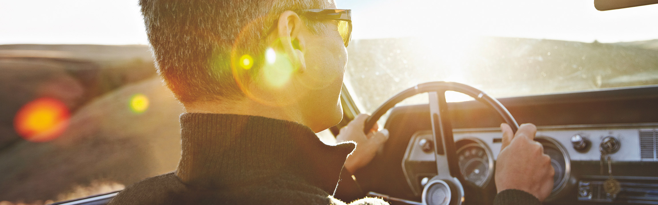 Close up of a man driving a convertible classic car with the roof down