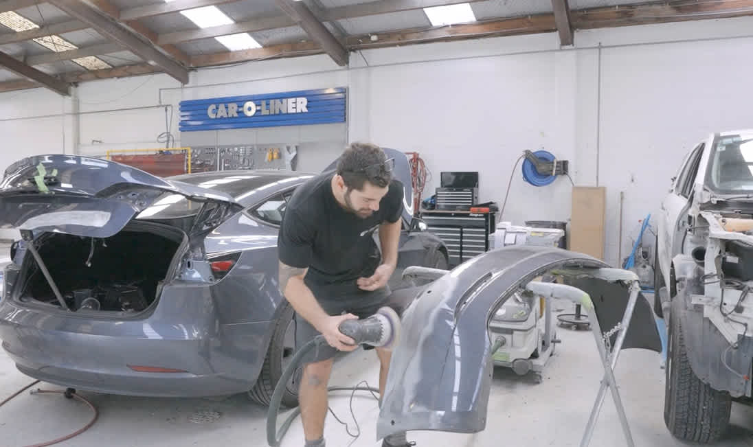 Apprentice buffing a car fender