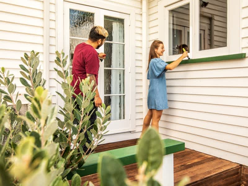 Young couple painting the outside of their home.