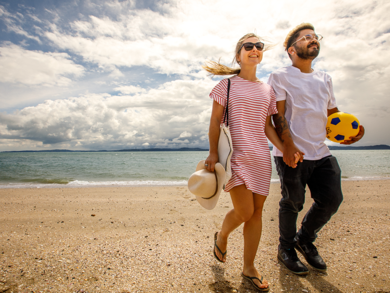 A couple in sunglasses walking along the beach.