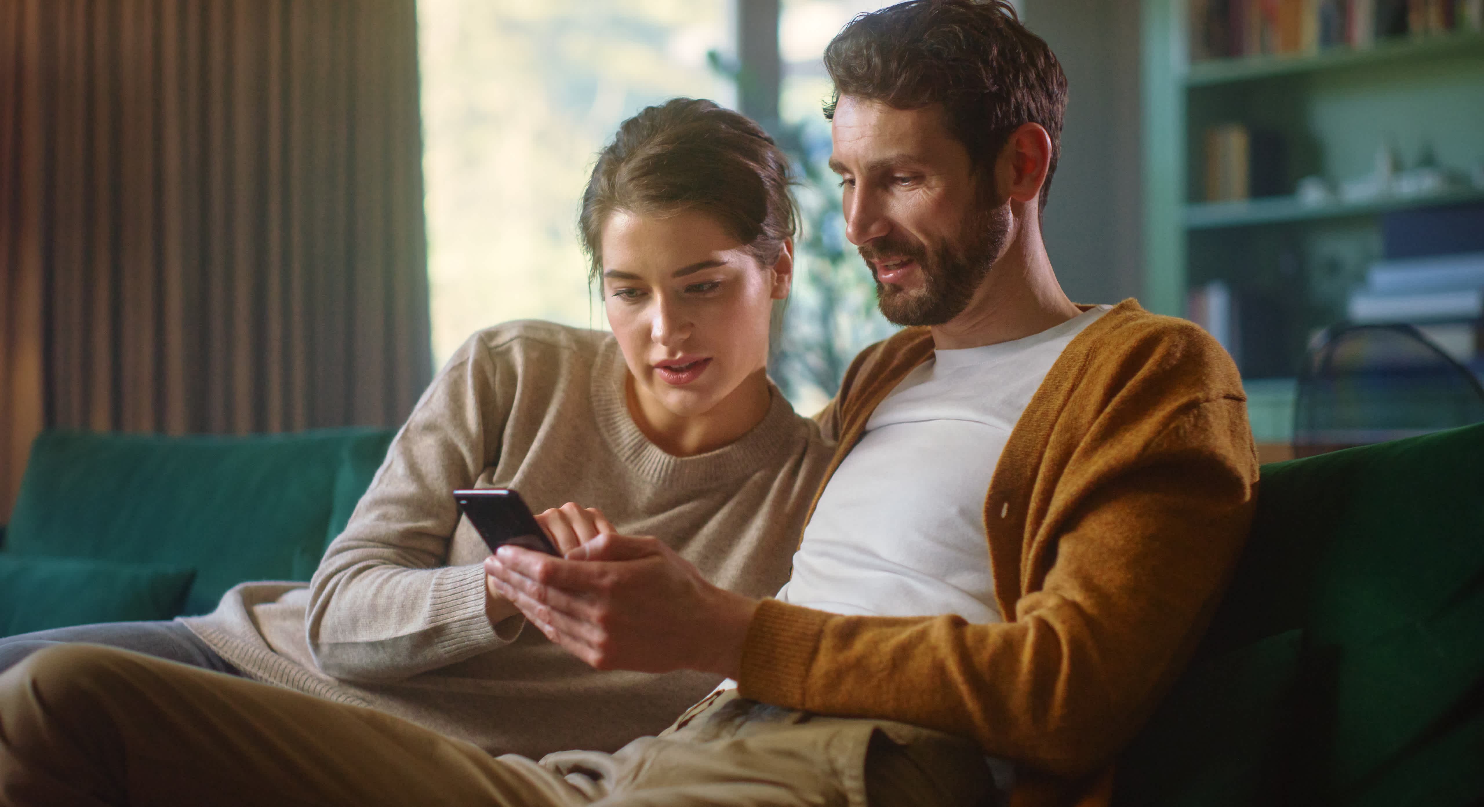 couple looking at mobile while sitting on couch together