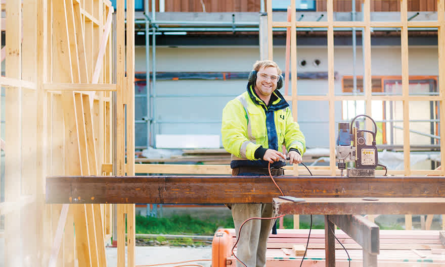 builder at construction site smiling to camera.