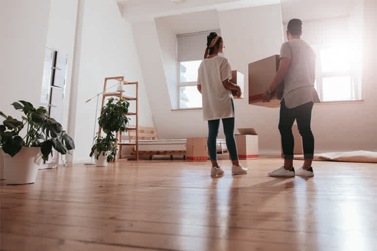 Couple setting down moving boxes in new apartment