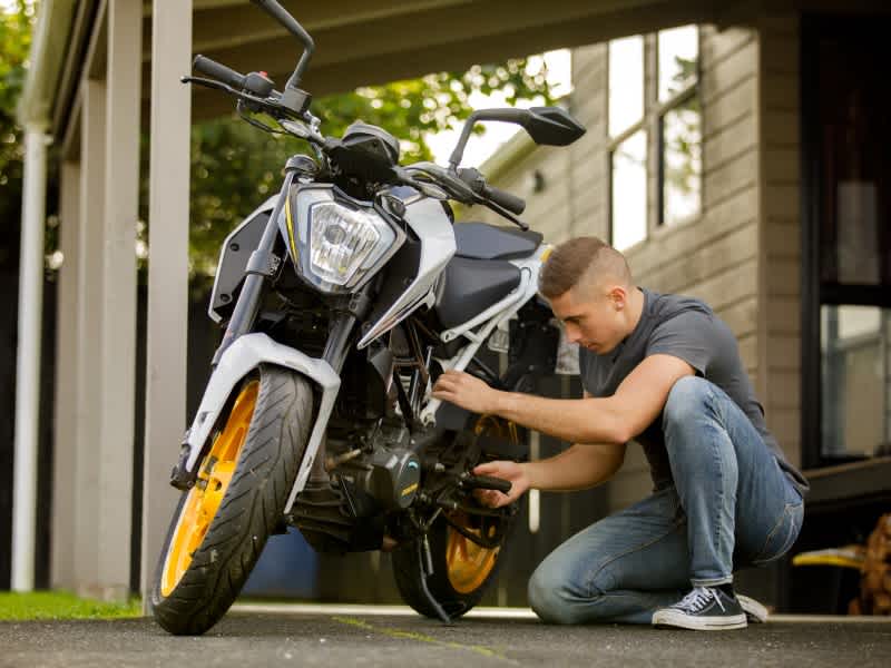 A man checking his motorcycle to ensure he's safe on the road.