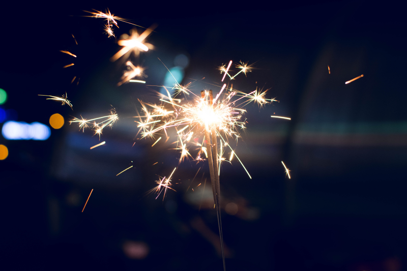 Sparklers being used outdoors at night, held at arms length.