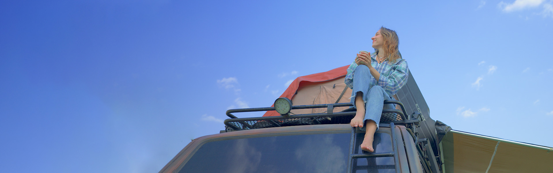 Person sitting on roof rack enjoying a view
