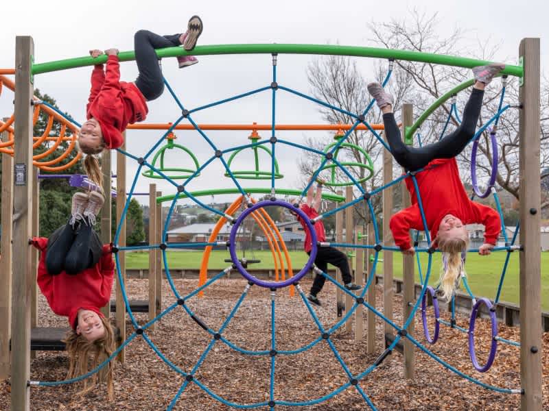 Four students of East Gore school having fun on a colourful climbing frame.