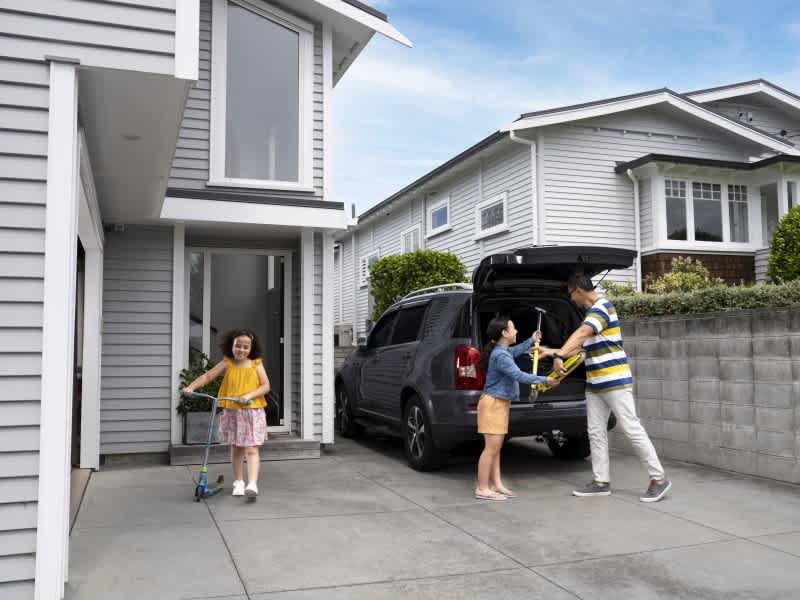 Two girls coming out of their Dad's car with their scooters.